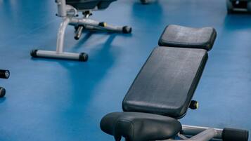 A gym with exercise equipment and a blue floor.