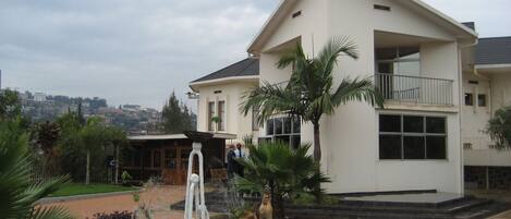 A two-story house with a balcony, a fountain, and a landscaped garden.