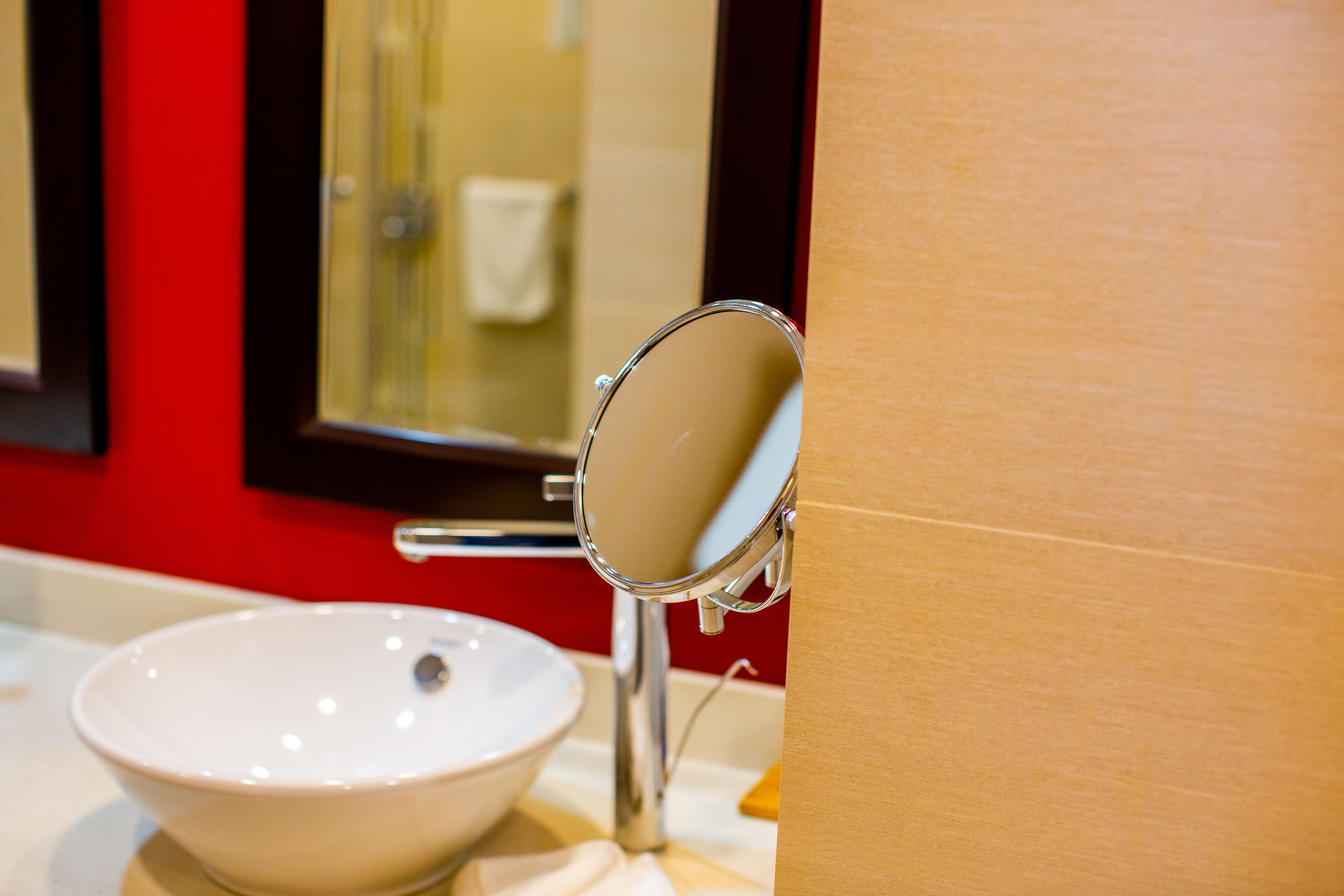 A bathroom with a white sink, a mirror, and a red wall.