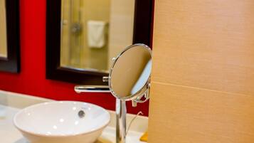 A bathroom with a white sink, a mirror, and a red wall.