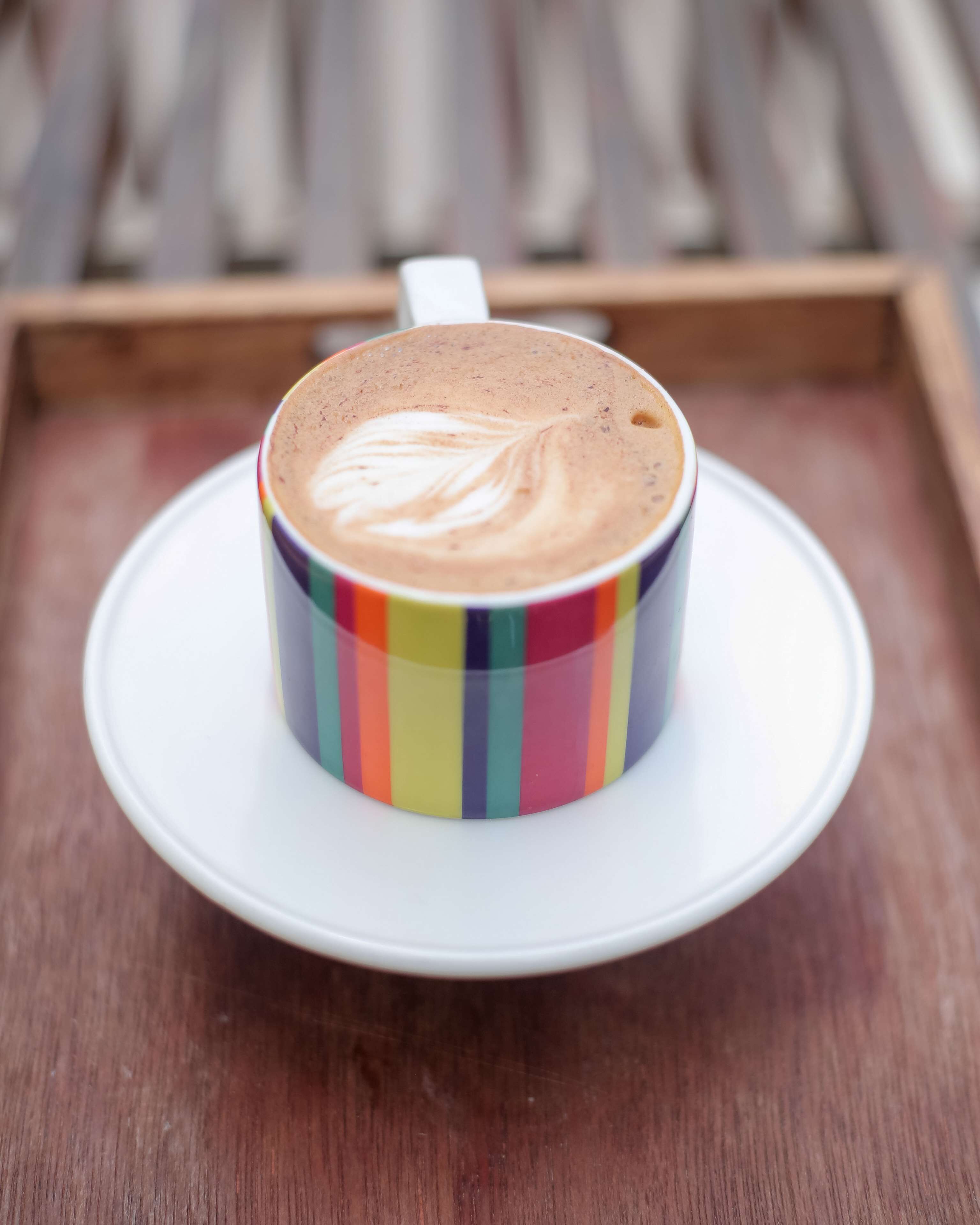 En kop kaffe på en hvid underkop på en træbakke.