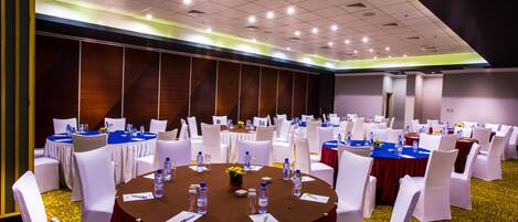A conference room with round tables, white chairs, and blue tablecloths.
