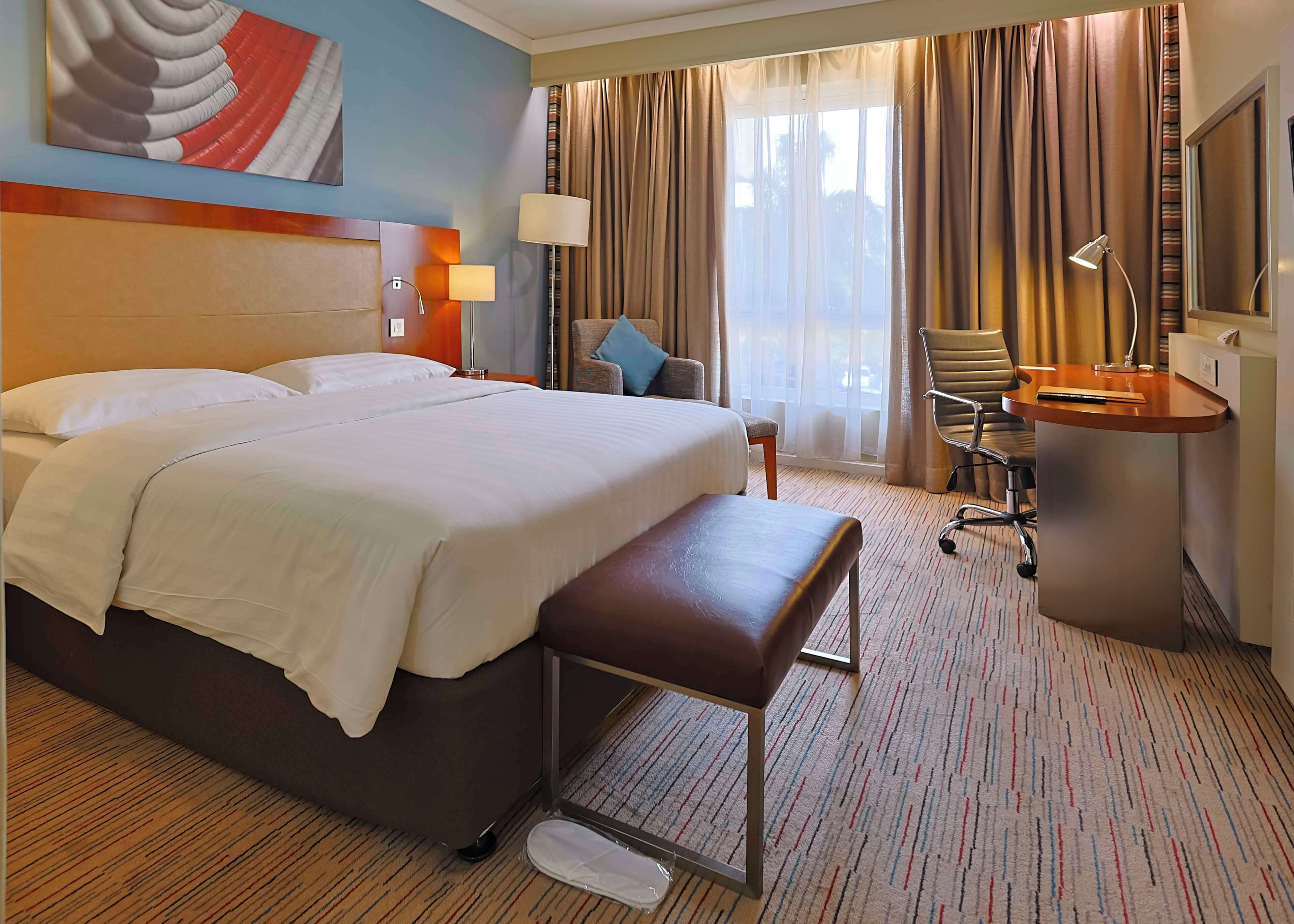 A hotel room with a large bed, a desk, a chair, and a television.