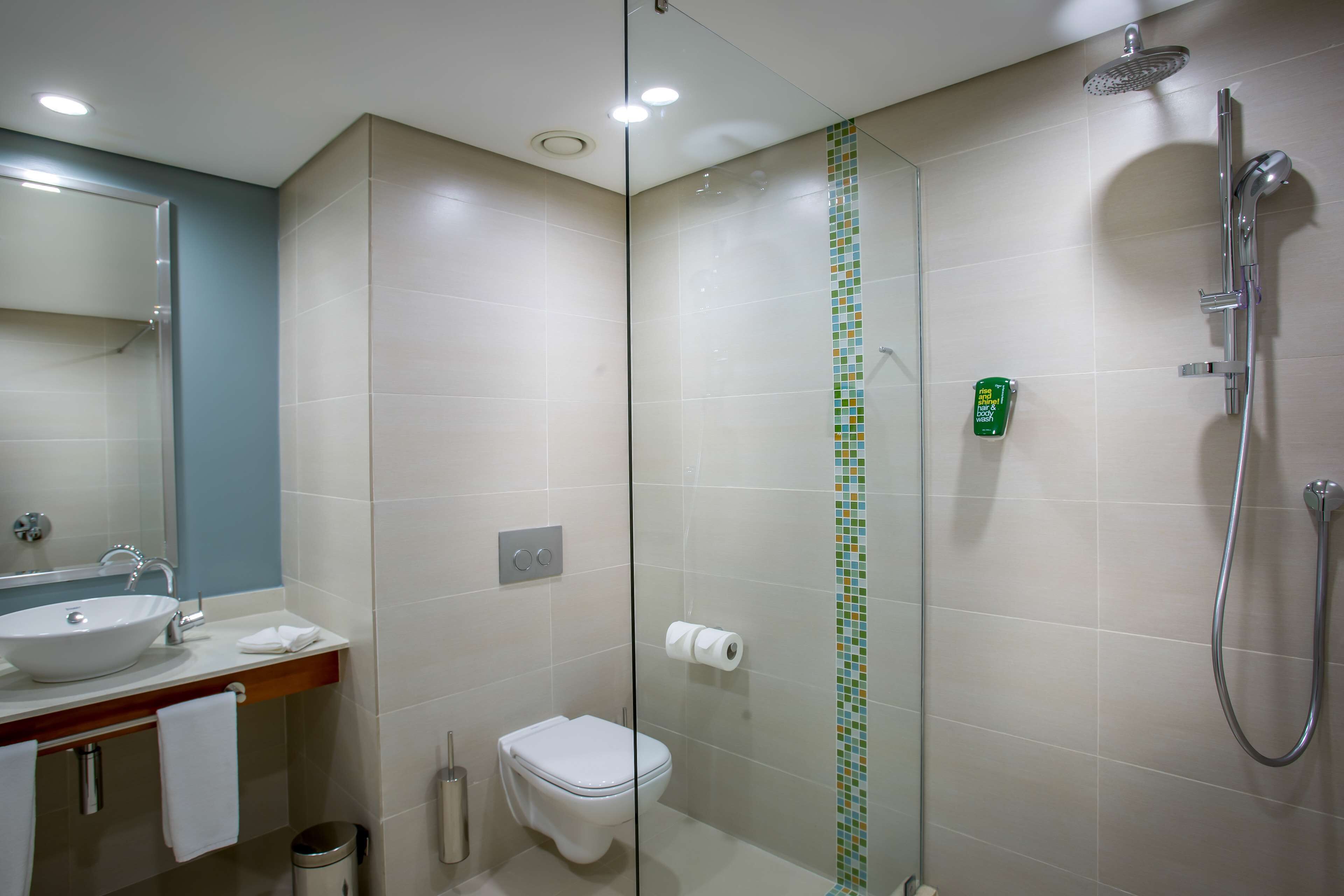 A modern bathroom with a glass shower enclosure, a sink, and a toilet.