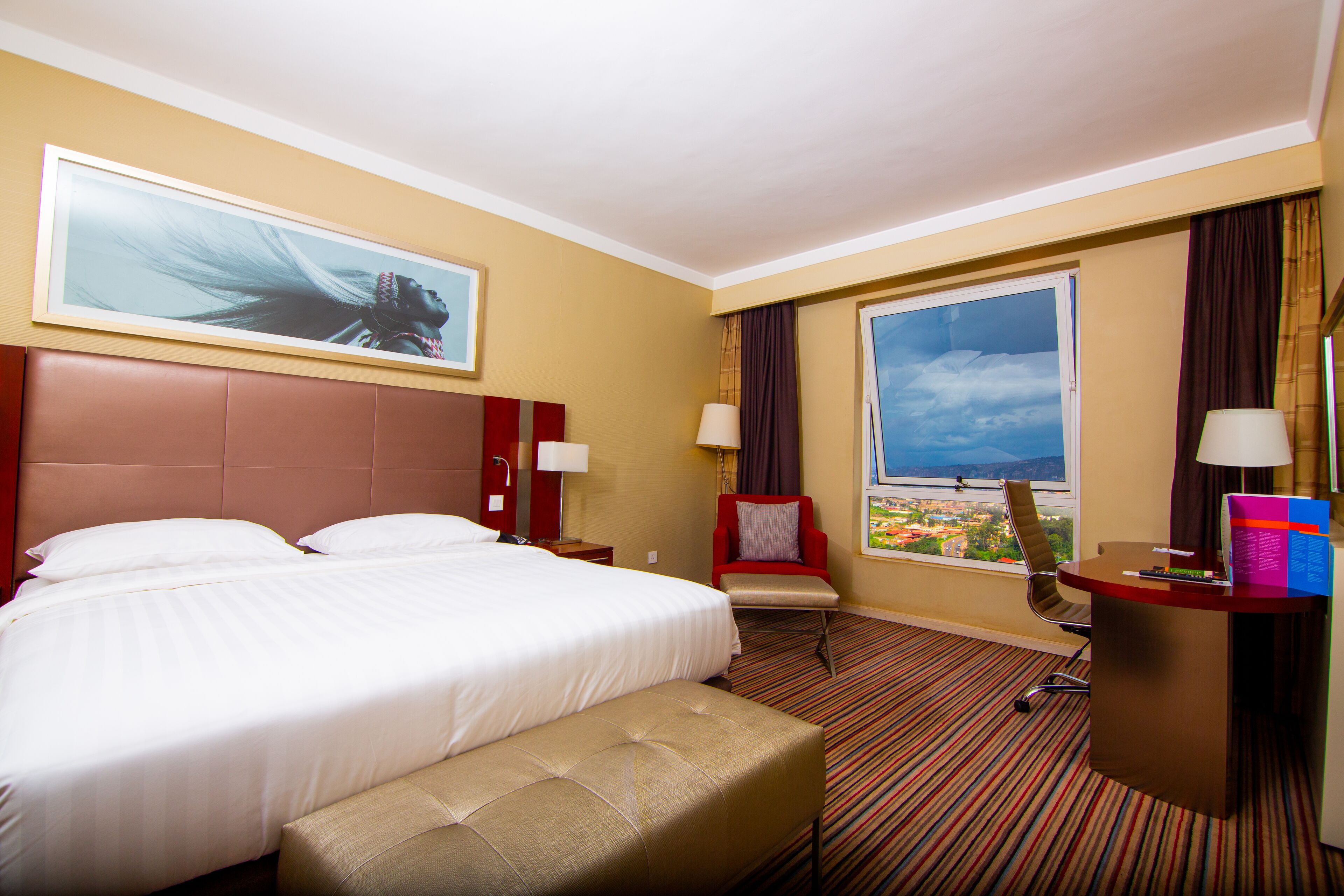 Una habitación de hotel con una cama grande, un escritorio, una silla y una ventana con vista a la ciudad.