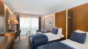 A hotel room with two beds, a desk, a chair, a small table, and a large window with curtains.
