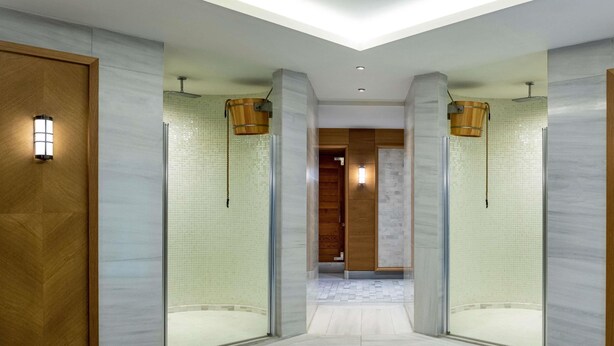 Un moderno vestíbulo de hotel con un pasillo central, puertas de madera y separadores de vidrio.