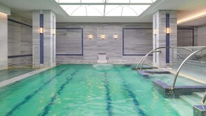 Una piscina interior con agua cristalina, rodeada de paredes y columnas de azulejos, bajo una claraboya.