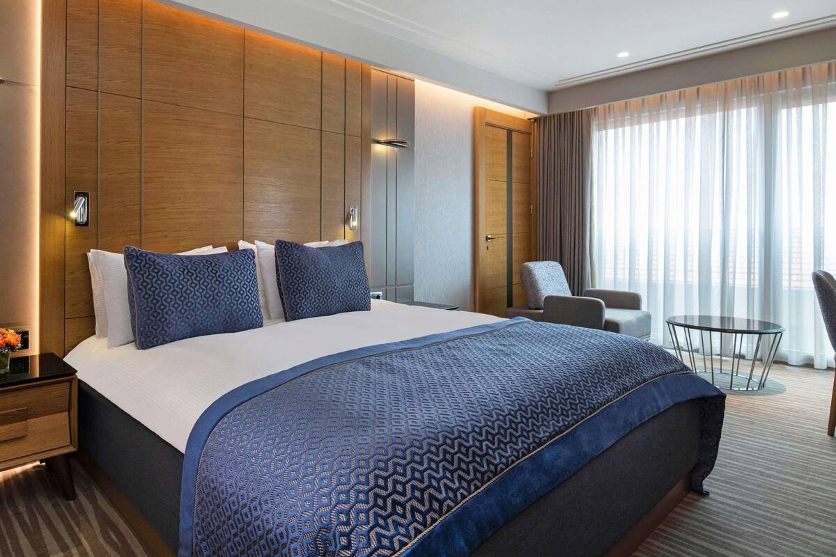 Une chambre d’hôtel avec un grand lit, un bureau, une chaise et une petite table.