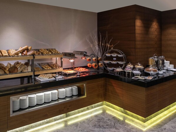 Un bufé con diversos alimentos, una estación de café y una presentación de platos.