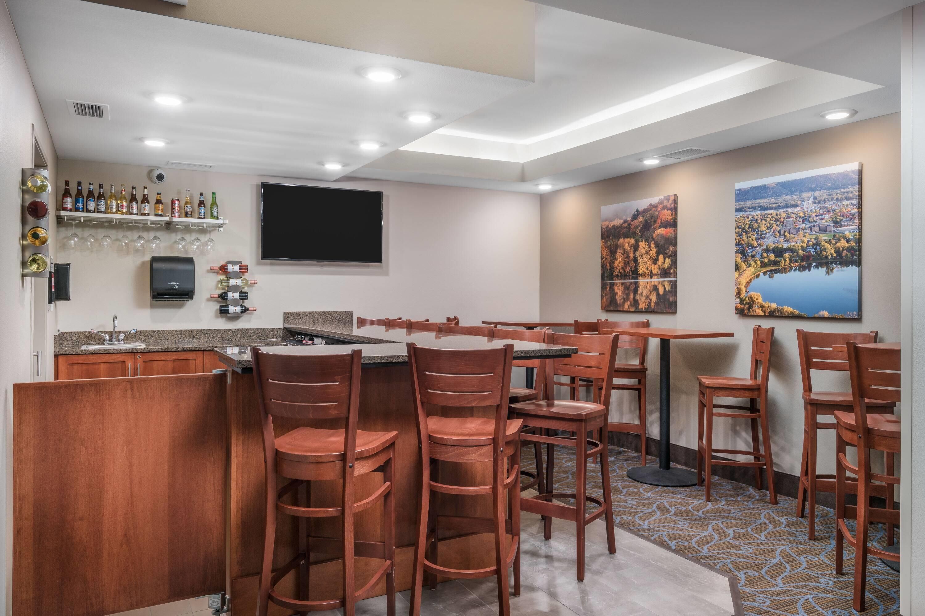 Een hotelbar met houten stoelen, een bar en een aan de muur bevestigde televisie.