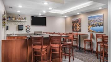 Een hotelbar met houten stoelen, een bar en een aan de muur bevestigde televisie.