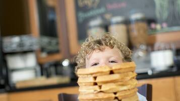 A child with a plate of pancakes in a kitchen.