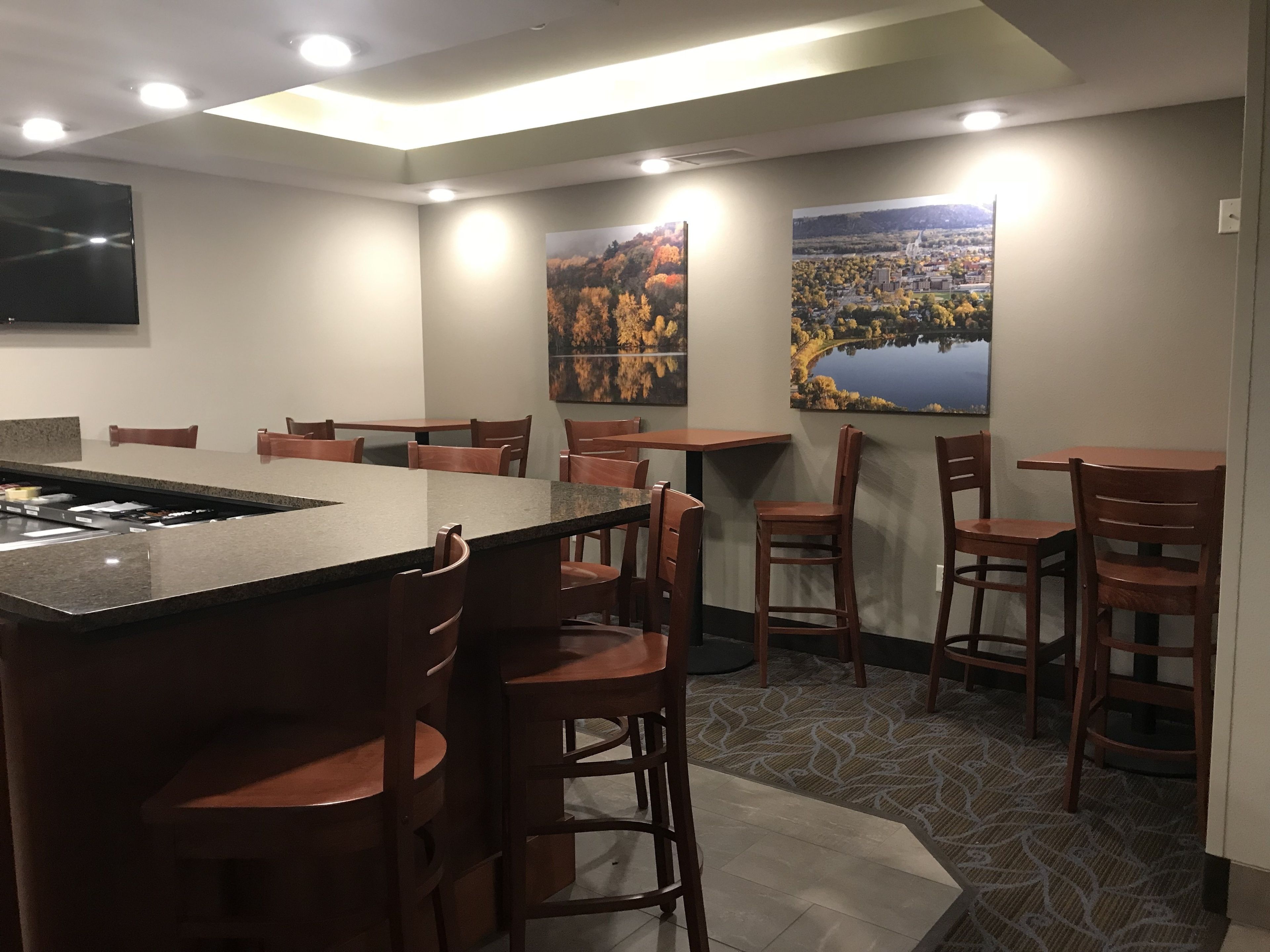 A restaurant with a central island bar, multiple seating areas, and two large paintings on the walls.