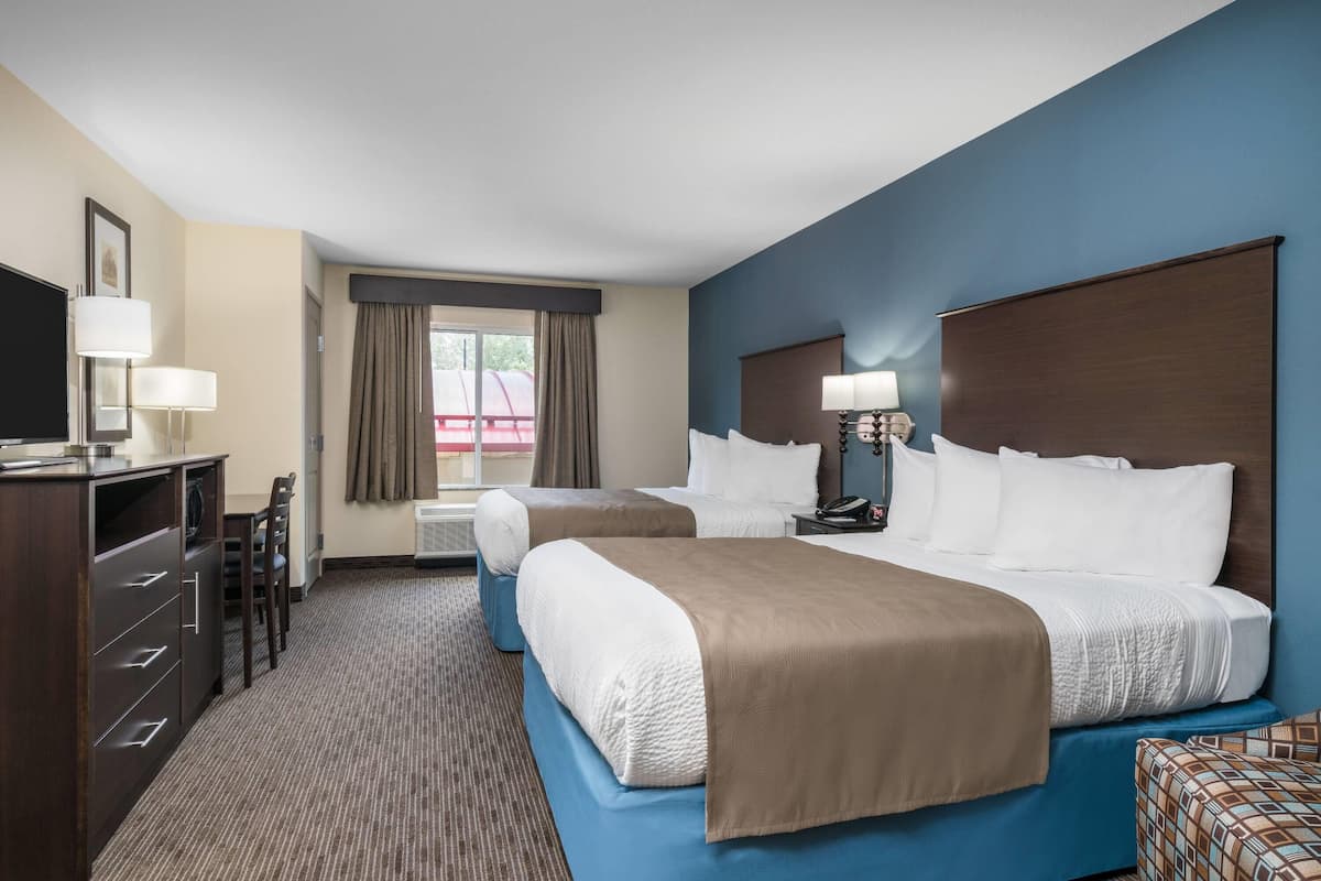 A hotel room with two beds, a desk, and a TV.