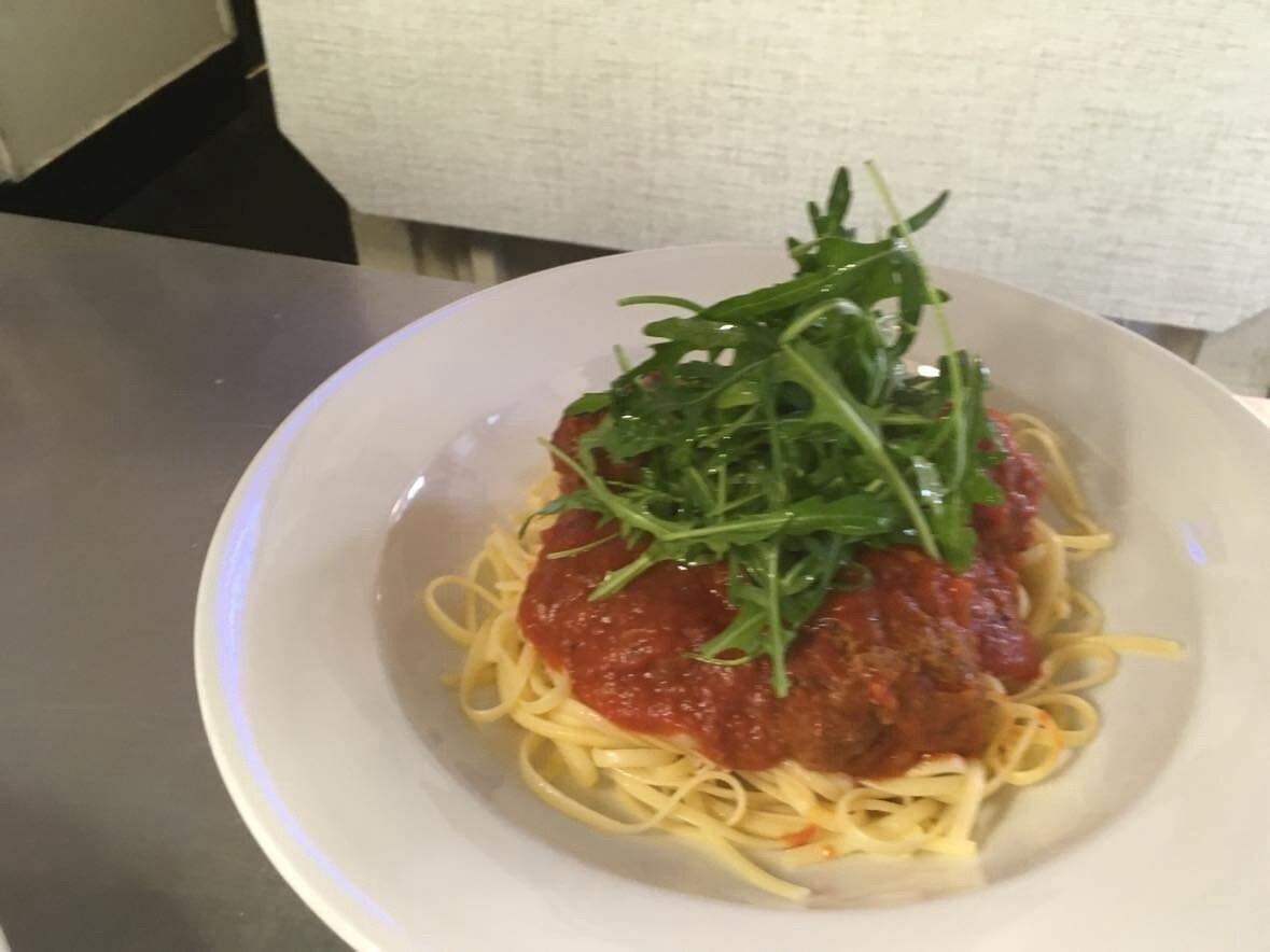 Une assiette de spaghettis à la sauce tomate, garnie de verdure.
