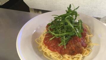 Une assiette de spaghettis à la sauce tomate, garnie de verdure.