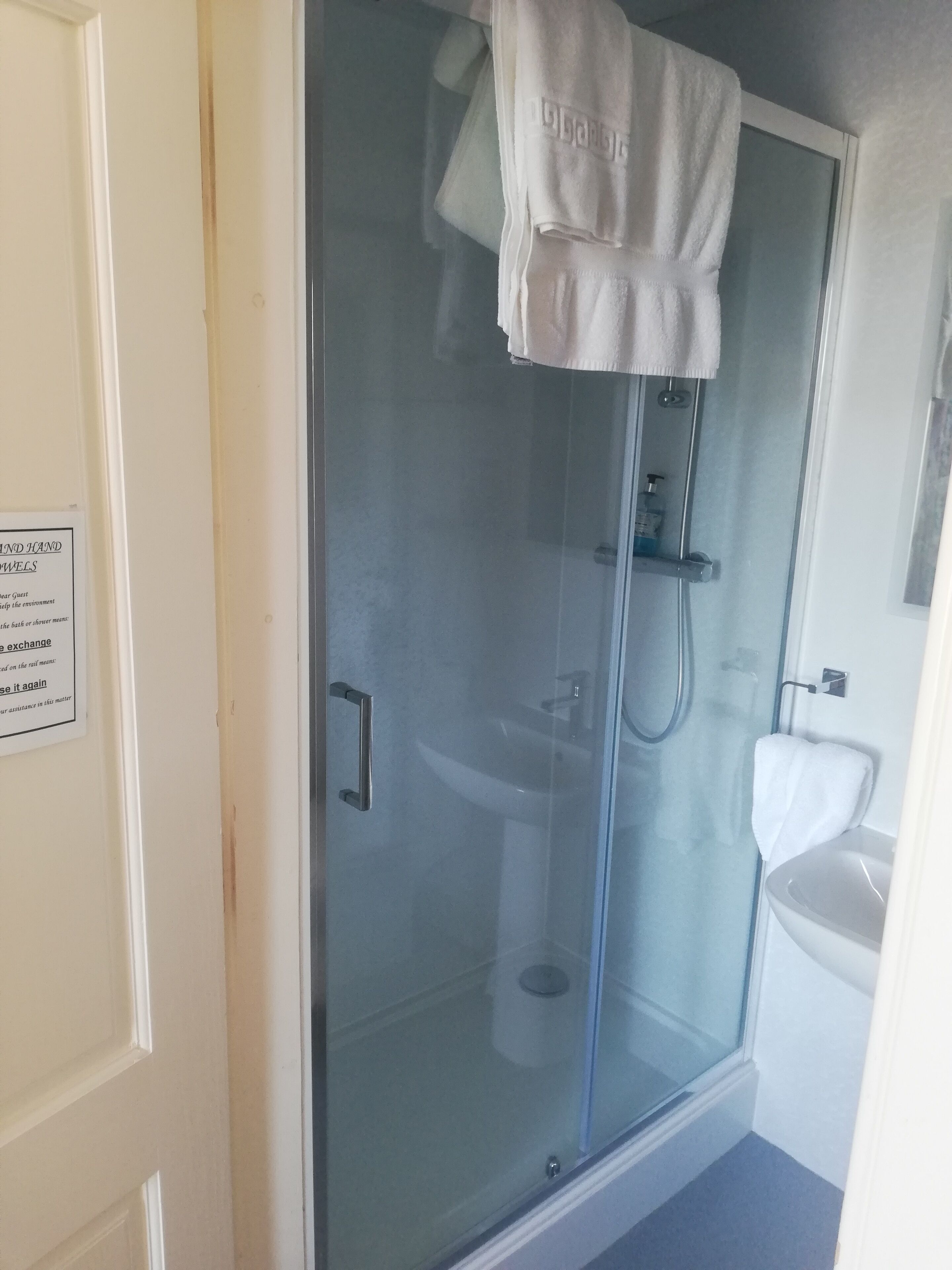 A glass-enclosed shower area with a white towel hanging on the door handle.