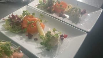 Una mesa de comedor con tres platos cuadrados de comida, cada uno con diferentes preparaciones.