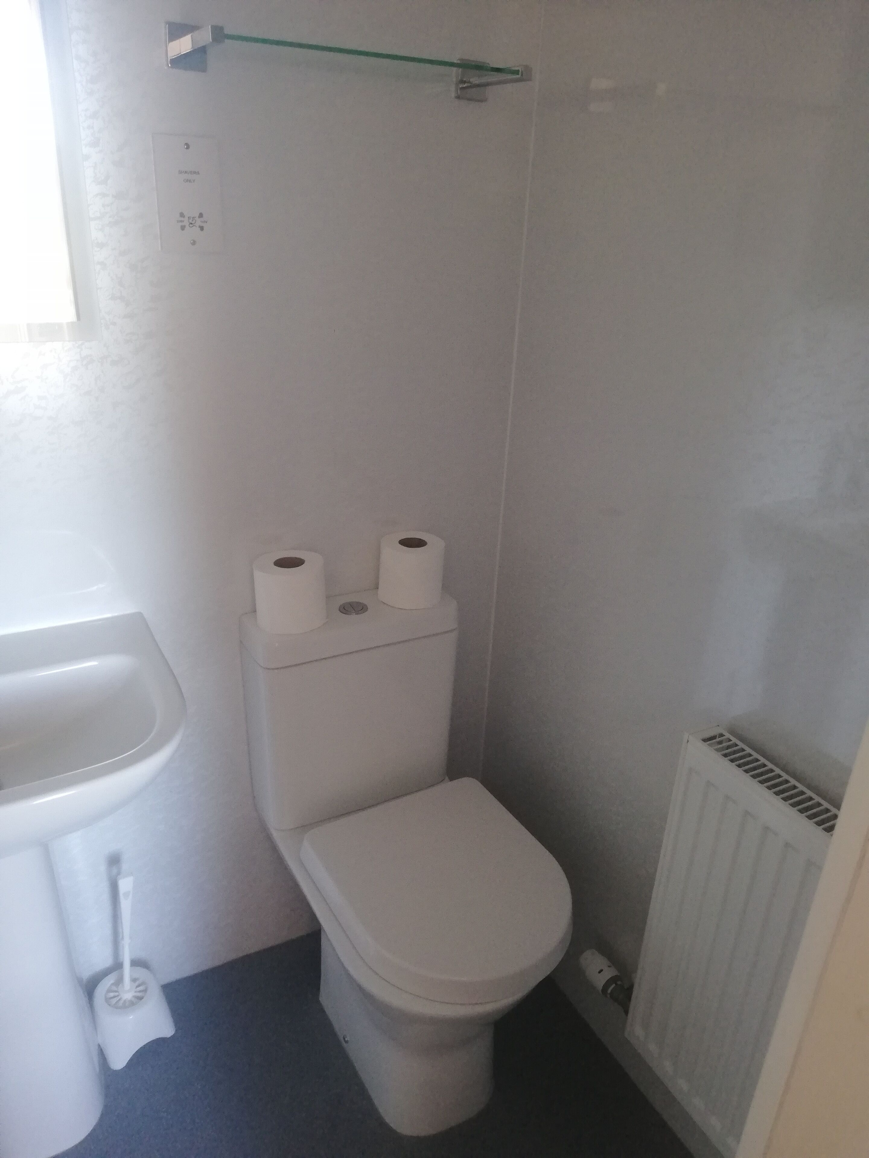 Ein kleines, weißes Badezimmer mit Toilette, Bidet und Heizkörper.