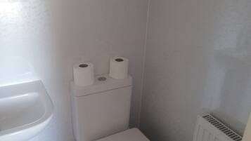 Ein kleines, weißes Badezimmer mit Toilette, Bidet und Heizkörper.