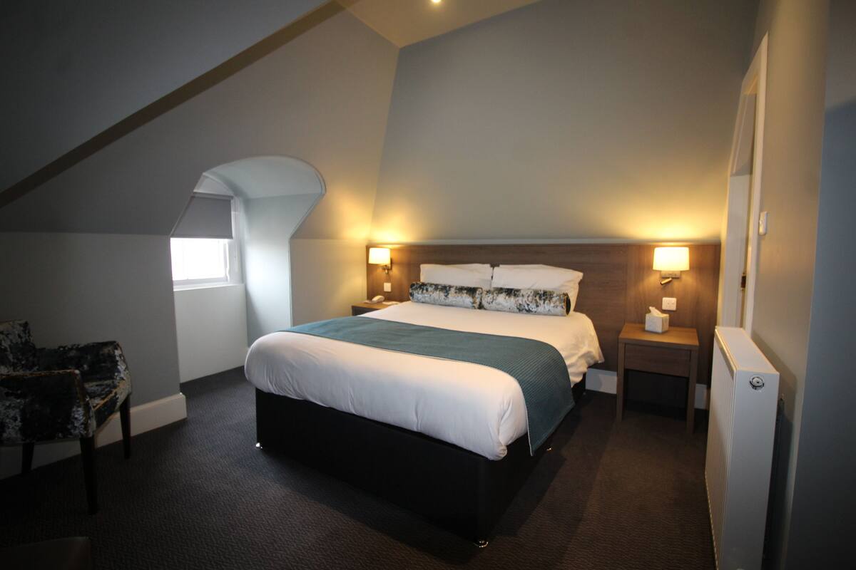 Ein Schlafzimmer mit einem großen Bett, zwei Nachttischen, einem Sessel und einer Heizung.