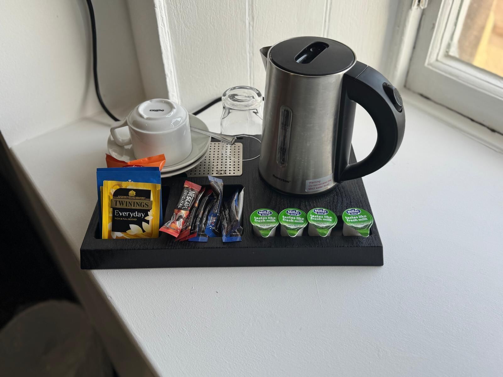 A kitchen counter with a kettle, teapot, and various food items including tea bags and milk cartons.