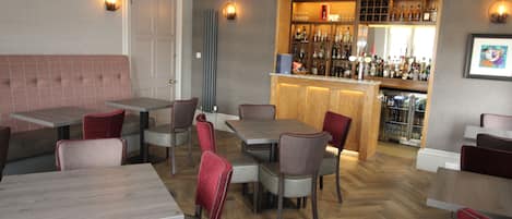 Un restaurante con zona de bar, asientos disponibles y señal de salida de incendios.