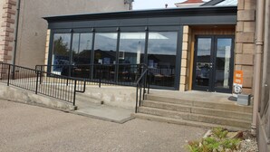 A building with large windows, a black door, and a sign that says "Great Coffee".
