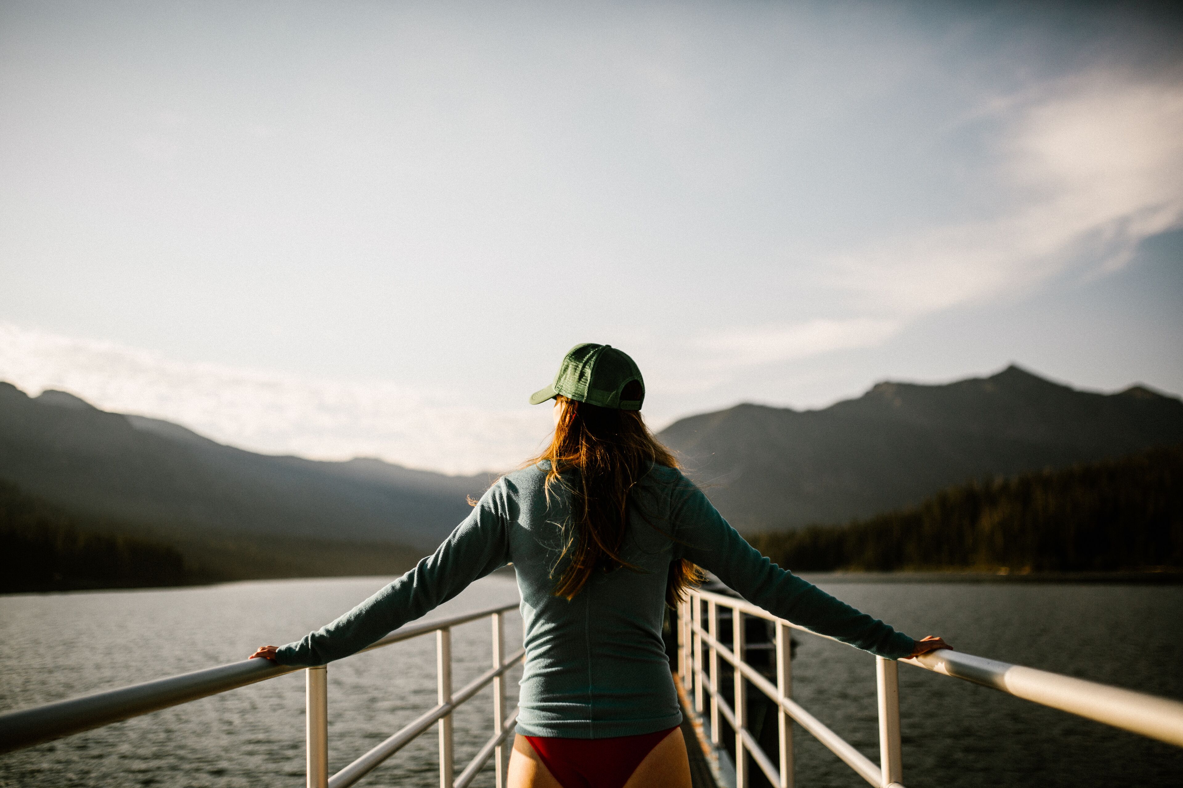 A person standing on a boat with a view of mountains and a lake.