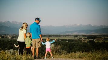 A family of four standing on a dirt path with a mountainous landscape in the background.