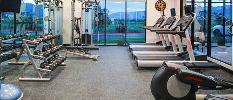 Ein Fitnessstudio mit Laufbändern, Hanteln und Krafttrainingsgeräten.