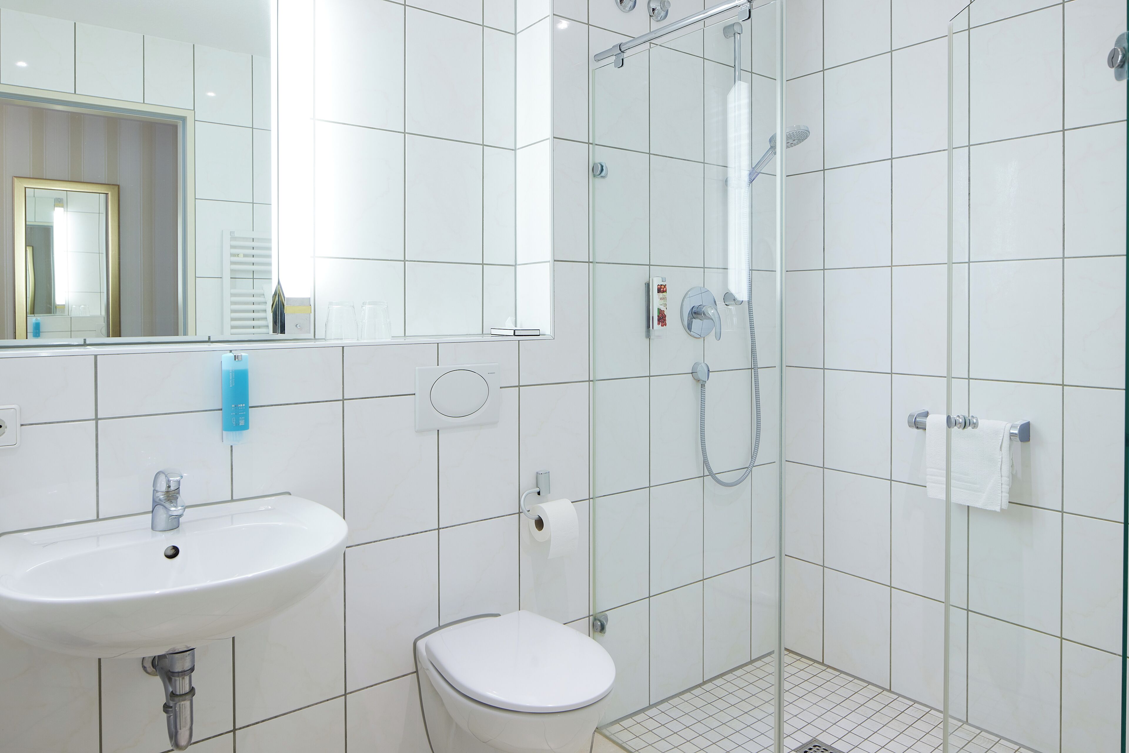 A modern bathroom with a white sink, toilet, and glass-enclosed shower.