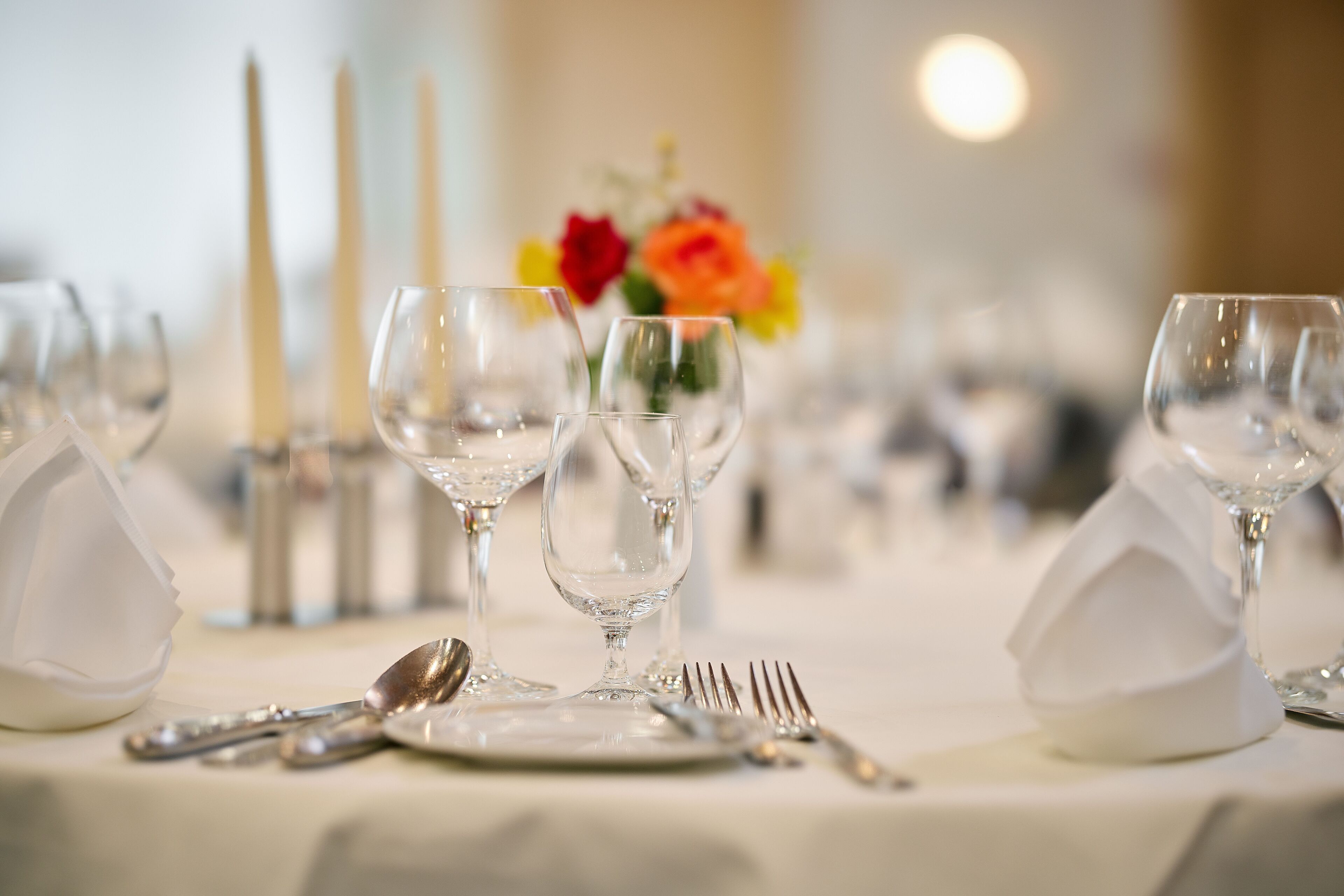 A table set for dining with clear glassware, silverware, and white napkins.