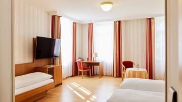Una camera d'albergo con un letto, una scrivania con una sedia, una televisione e un tavolino con una sedia.