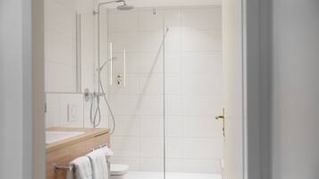 A modern bathroom with a shower, toilet, and sink.