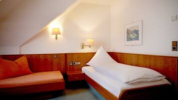 A hotel room with a wooden headboard, a single bed, a wooden nightstand, a lamp, and a framed picture on the wall.