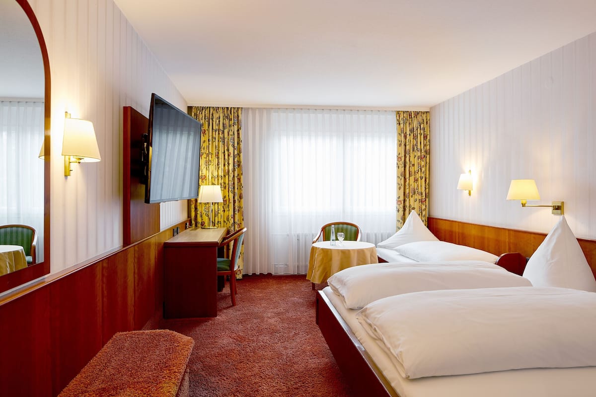 Una habitación de hotel con una cama grande, un escritorio, una silla, una mesita y un televisor.