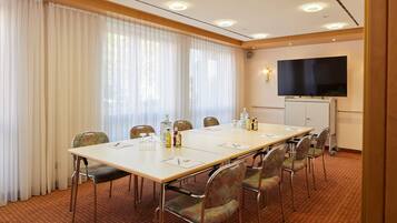 A conference room with a long table, chairs, a flat-screen TV, and a whiteboard.