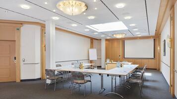 A conference room with a long table, chairs, a projector screen, and a whiteboard.