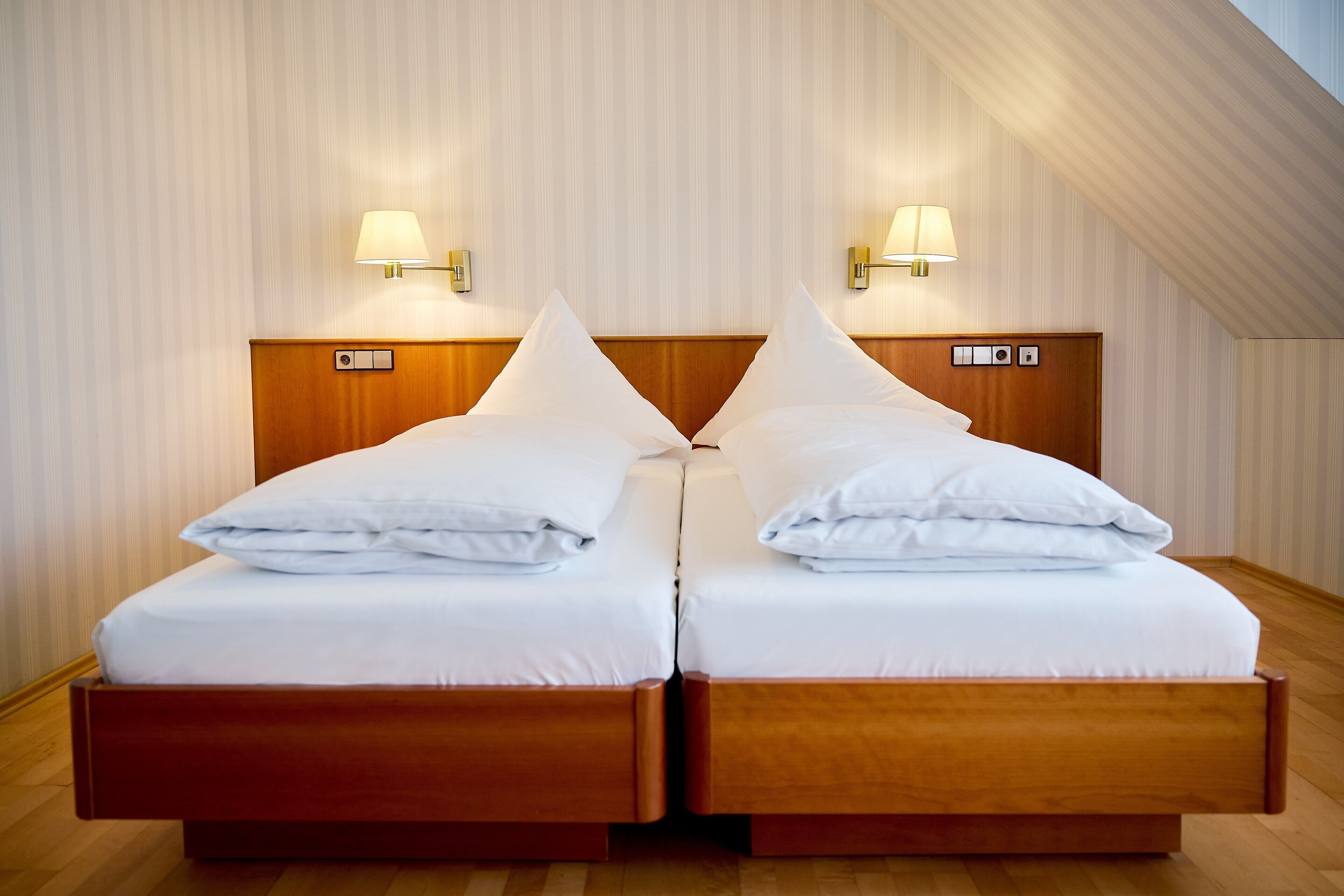 Un letto matrimoniale con una testiera in legno, due abat-jour e un pavimento in legno.