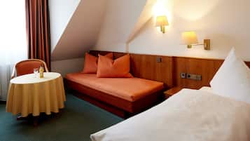 Une chambre d’hôtel avec un lit, une petite table sur laquelle se trouvent une bouteille et un verre, et une chaise.