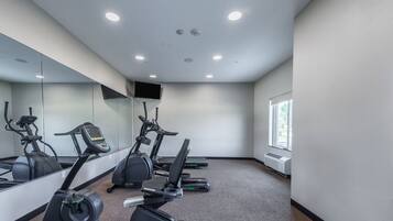 A gym with treadmills, a stationary bike, and a TV on the wall.