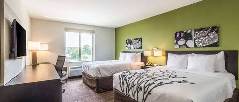 A hotel room with two beds, a desk, a TV, and artwork on the walls.