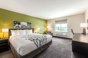 A hotel room with a large bed, a desk, a chair, and a window with a view.