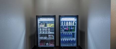 Dans un couloir, on trouve deux distributeurs automatiques de boissons, l’un portant l’inscription « Aliments surgelés » et l’autre « Boissons froides ».