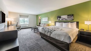 Quarto de hotel com uma cama grande, uma escrivaninha, uma cadeira e uma televisão.