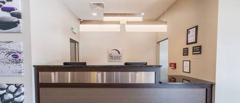 A reception desk with a modern design, a sign for 'Sleep Innsuites', and framed certificates on the wall.