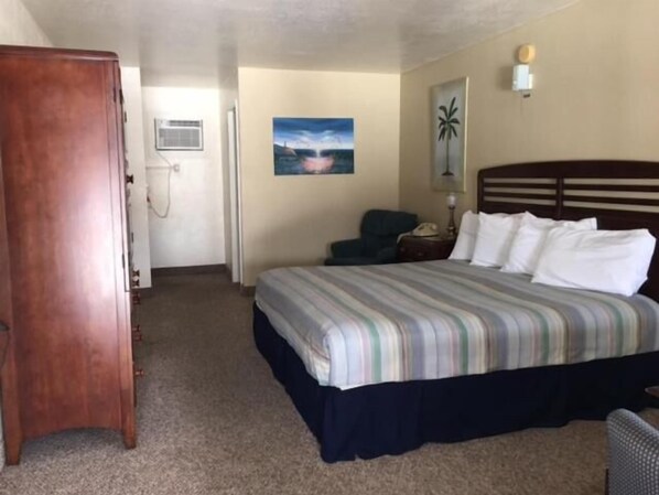 Una habitación de hotel con cama, escritorio, silla y armario.