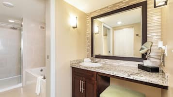 A bathroom with a large mirror, a sink, and a shower.